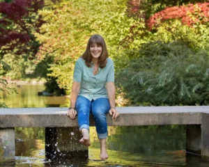 Silke mit Füßen im Wasser auf der Brücke